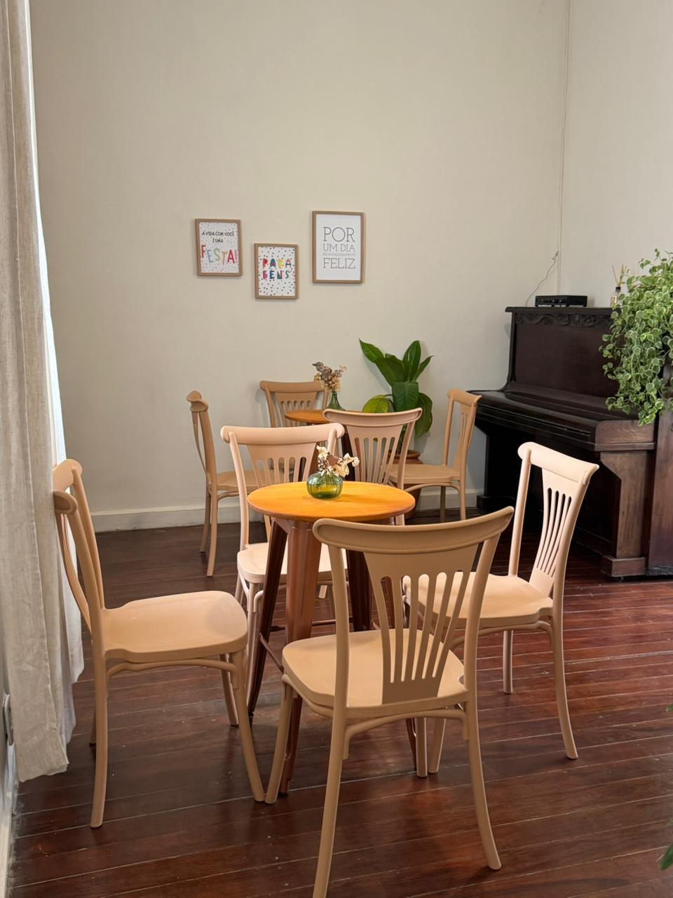 Mesas redondas com quadros motivacionais e piano ao fundo
