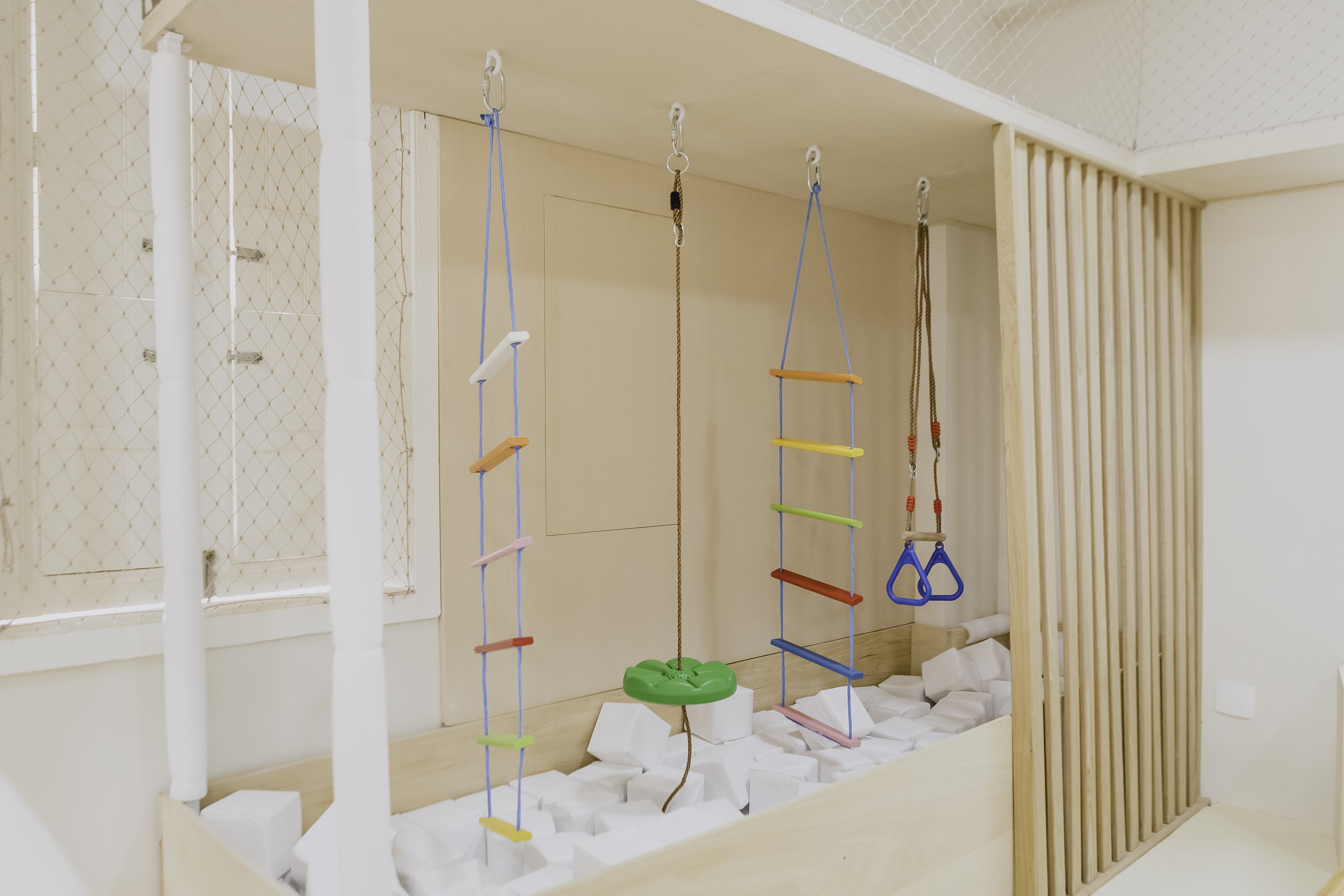 Escada de corda e argolas sobre piscina de blocos brancos