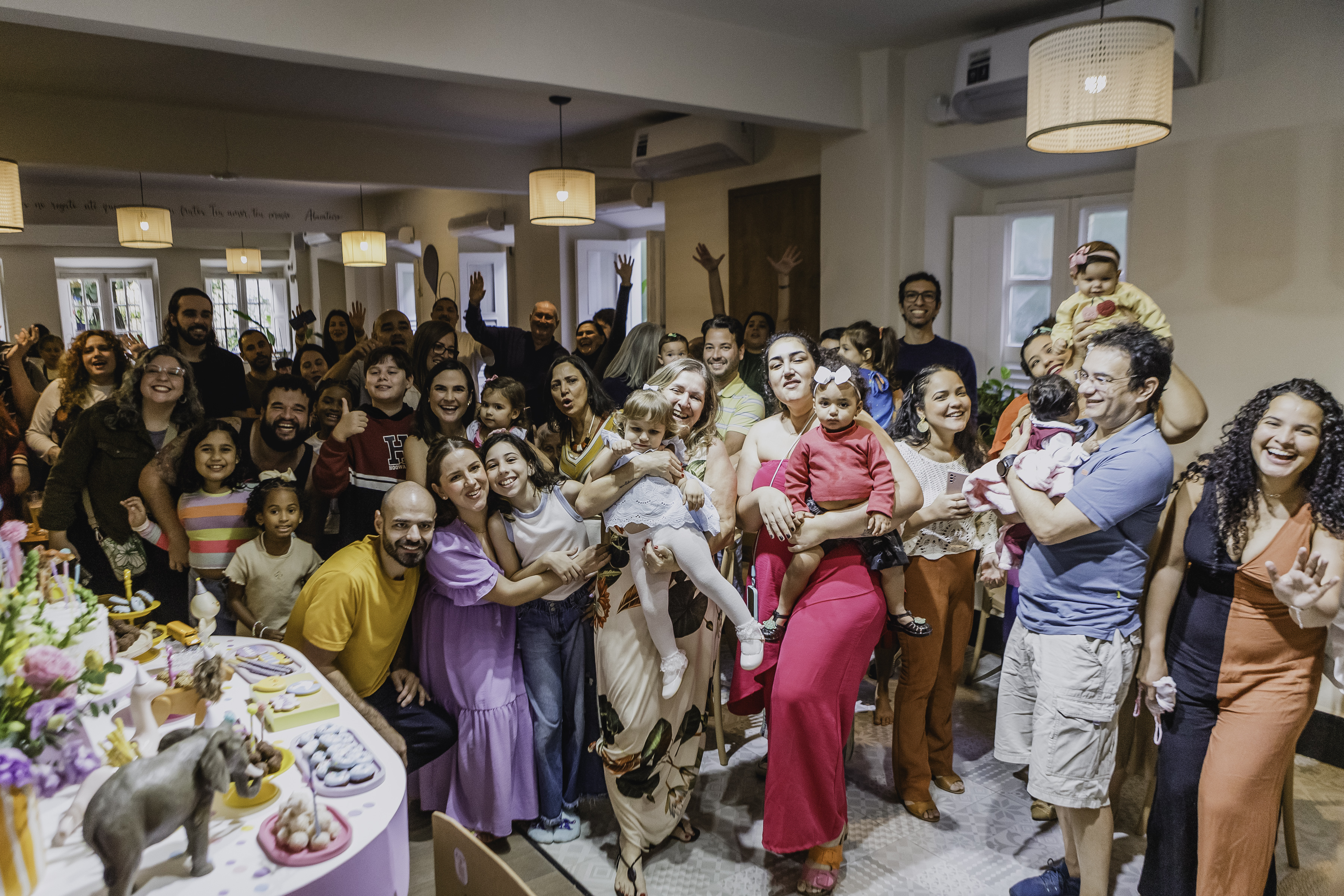 Grande grupo de convidados reunido e sorrindo para foto de festa