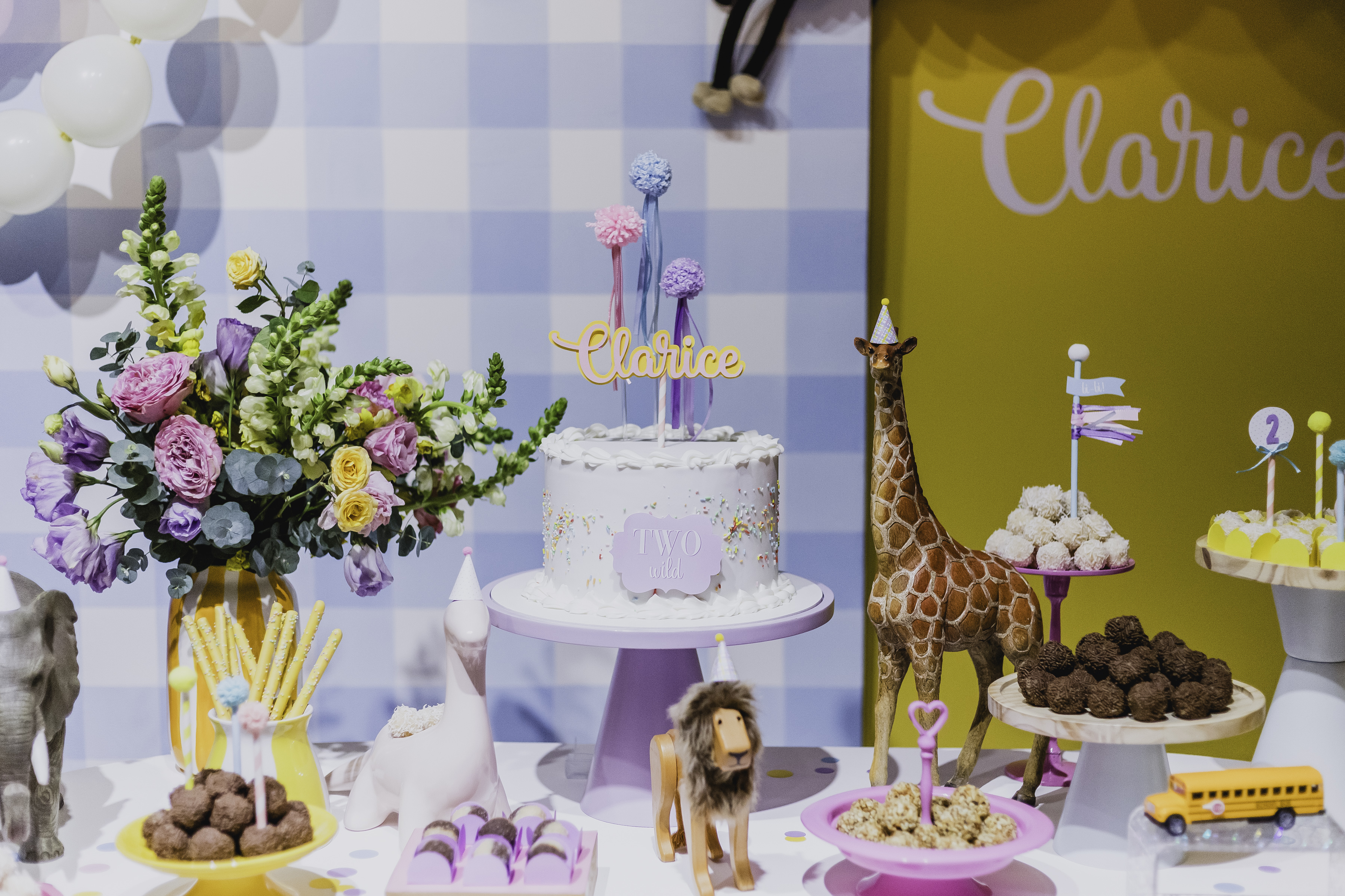 Mesa de doces com bolo, girafa e elefante decorativos em tema safari