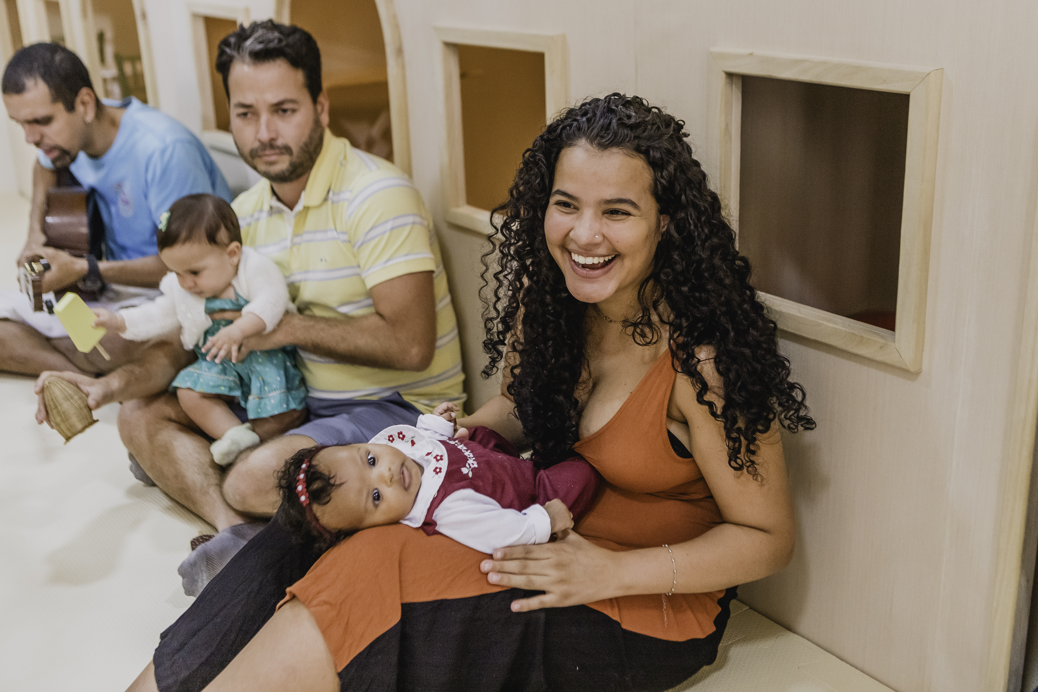 Pais sorrindo com bebês no colo durante a festa