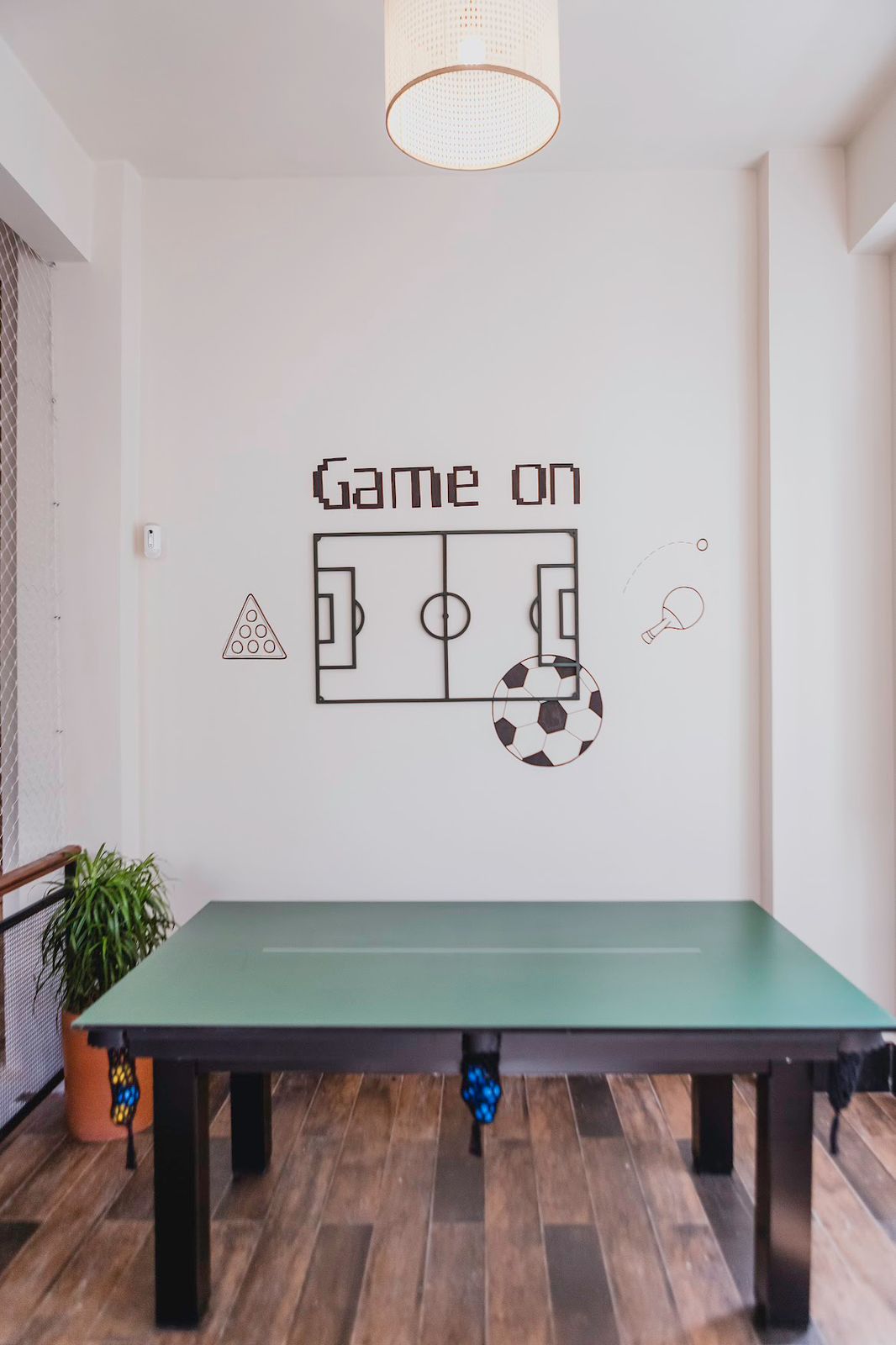 Sala de jogos com mesa de sinuca e ilustração Game on na parede
