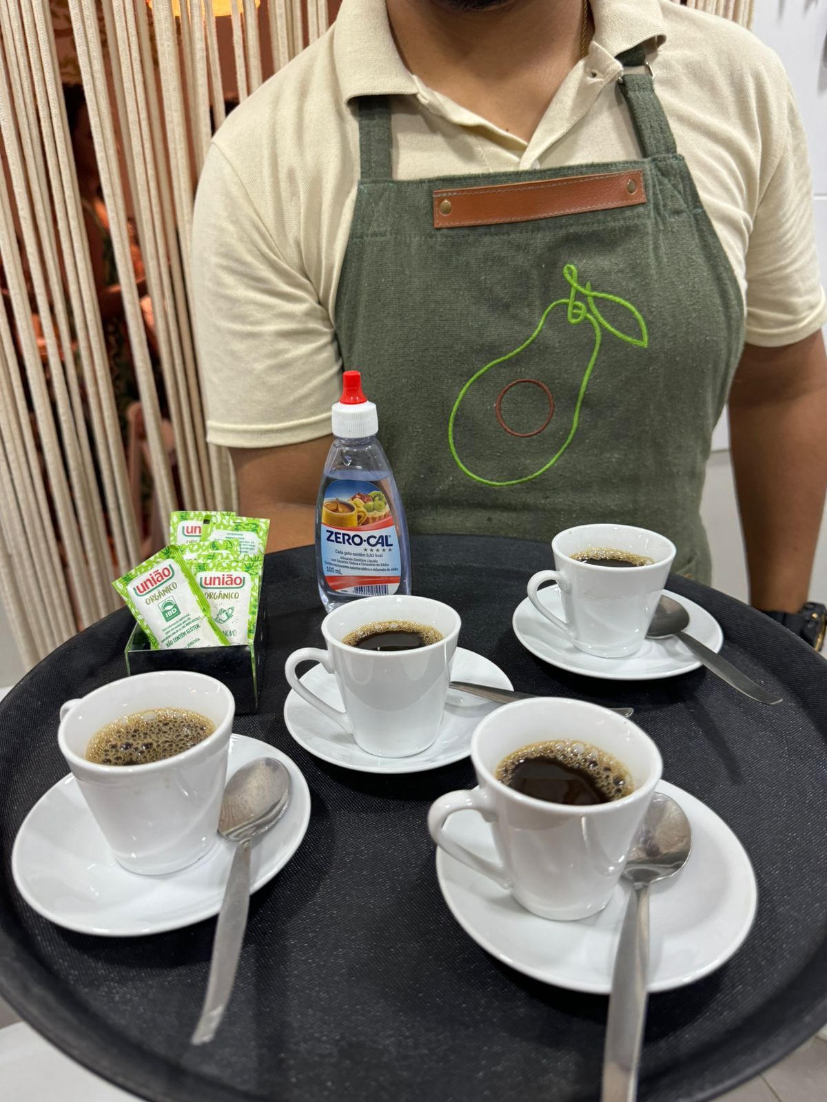 Garçom com avental do Abacateiro servindo bandeja de cafezinhos