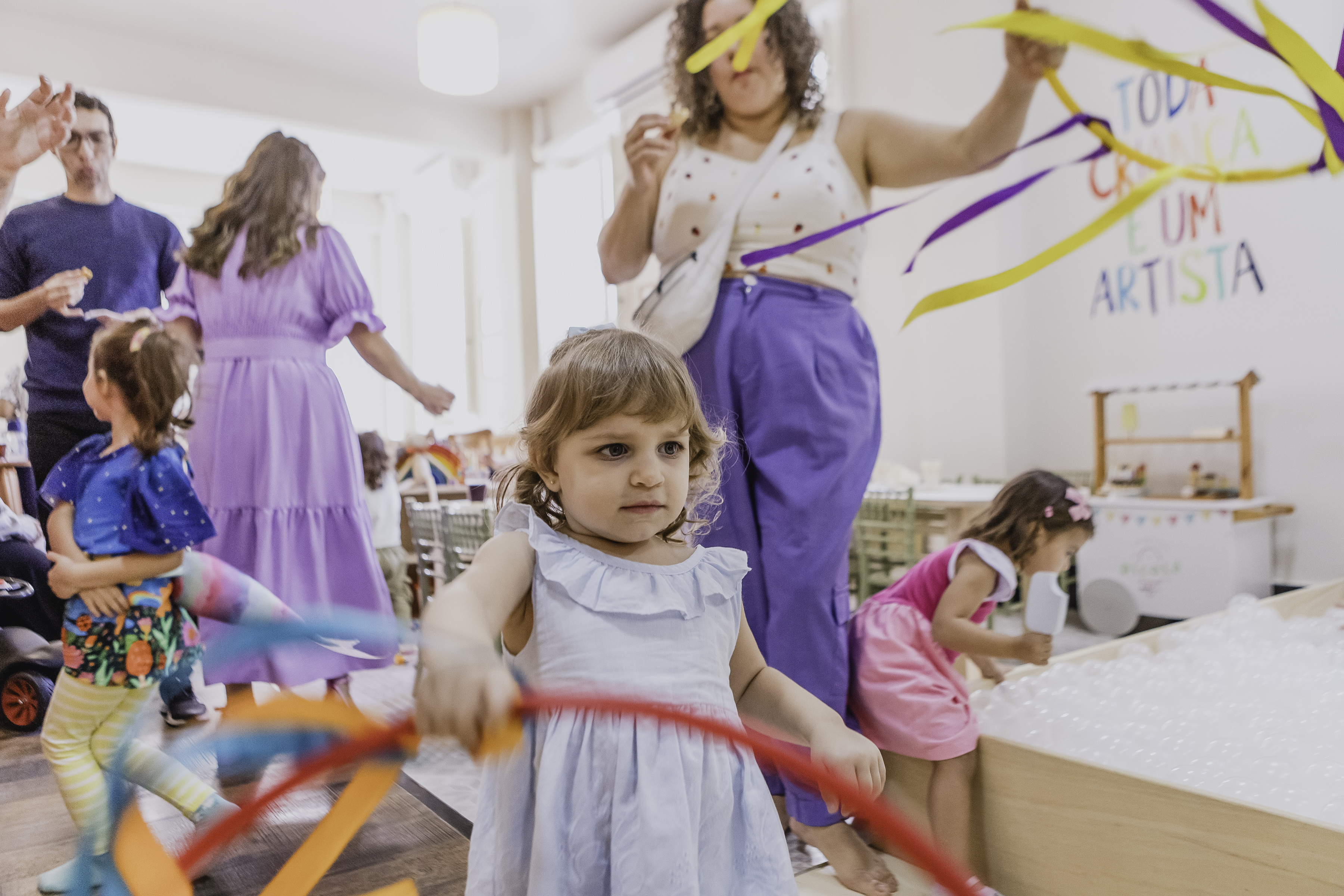 Crianças brincando com fitas coloridas em festa no Abacateiro