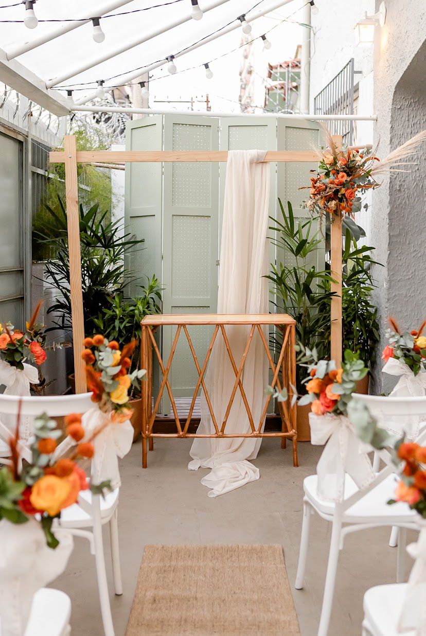 Altar de casamento com biombo verde, tecido e arranjo floral