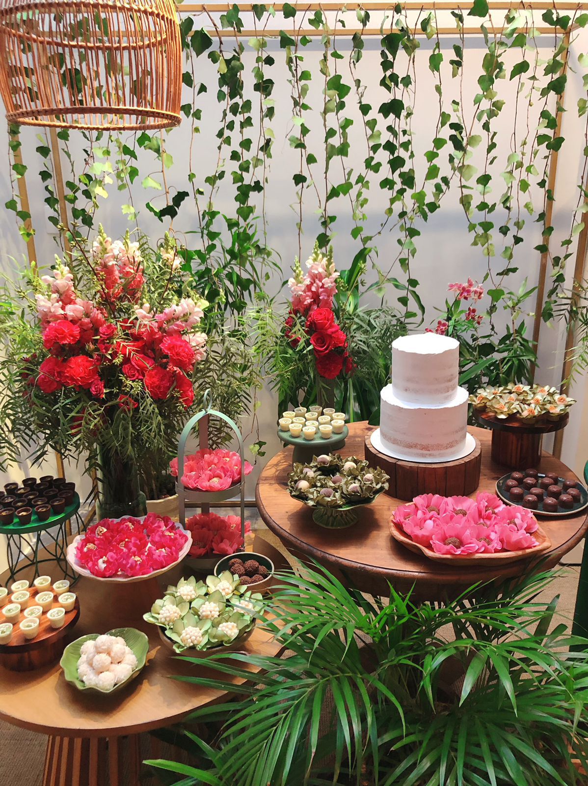 Mesa de doces com bolo, docinhos e flores penduradas