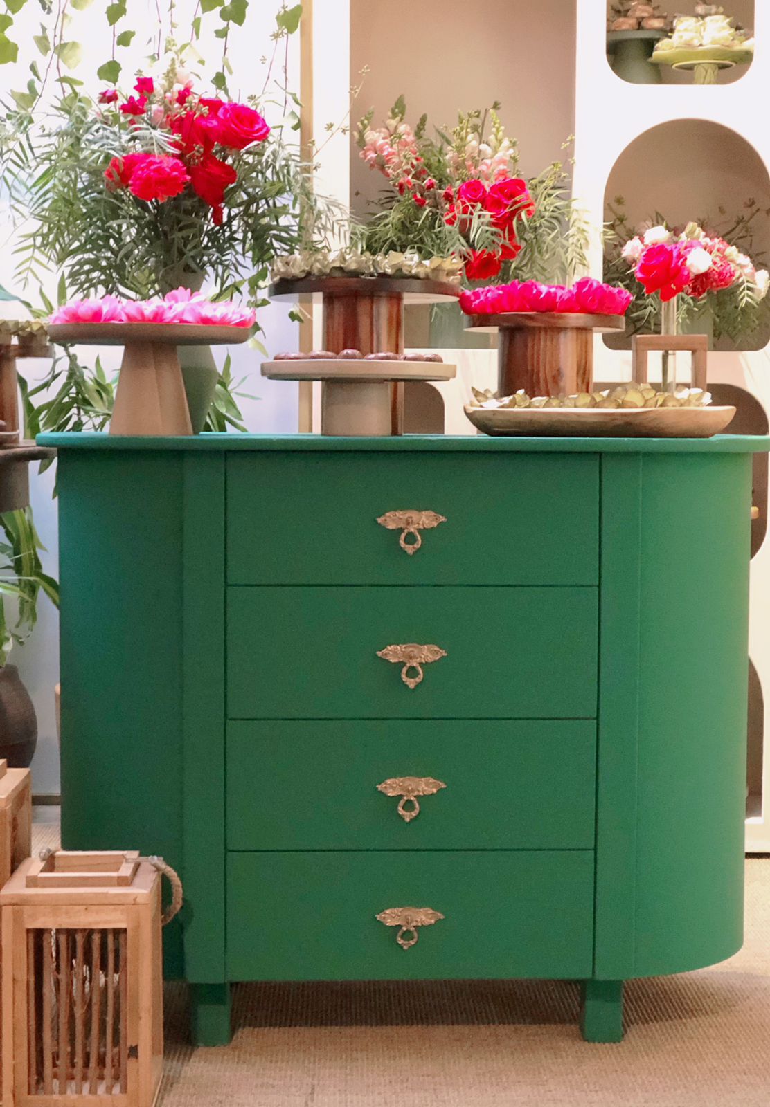 Cômoda verde usada como mesa de doces com flores vermelhas